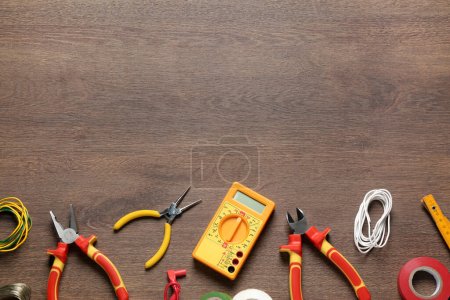 Foto de Diferentes alambres y herramientas de electricista en mesa de madera, tendido plano. Espacio para texto - Imagen libre de derechos