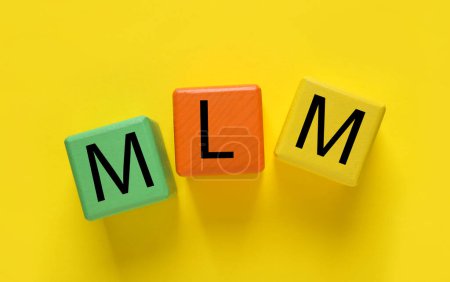 Téléchargez les photos : Marketing multi-niveaux. Abréviation MLM de cubes avec lettres sur fond jaune, vue du dessus - en image libre de droit