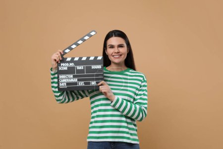 Foto de Actriz feliz con clapperboard sobre fondo beige. Industria cinematográfica - Imagen libre de derechos