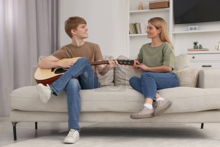 Teenage son playing guitar for his mother in living room