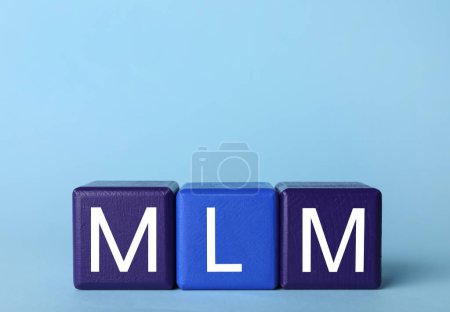Téléchargez les photos : Marketing multi-niveaux. Abréviation MLM de cubes avec lettres sur fond bleu clair - en image libre de droit