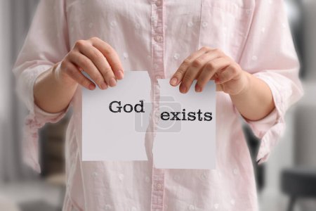 Téléchargez les photos : L'athéisme comme position religieuse. Femme déchirant du papier avec le texte Dieu Existe à l'intérieur, gros plan - en image libre de droit