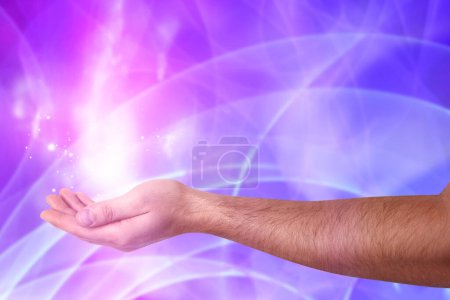Foto de Fenómenos Aura. Hombre con flujos de energía y luces alrededor de su mano contra el fondo de color, primer plano - Imagen libre de derechos