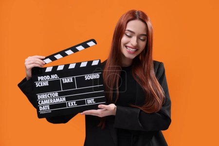 Foto de Feliz actriz con clapperboard sobre fondo naranja. Industria cinematográfica - Imagen libre de derechos