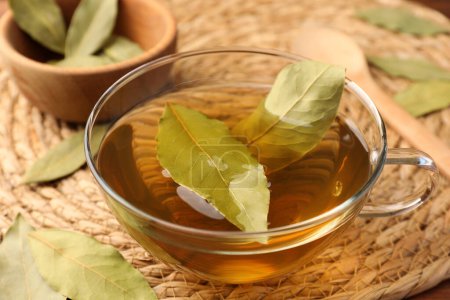 Téléchargez les photos : Tasse de thé fraîchement infusé avec des feuilles de laurier sur tapis d'osier, gros plan - en image libre de droit