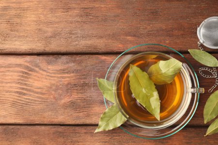 Téléchargez les photos : Tasse de thé fraîchement infusé avec des feuilles de laurier sur une table en bois, plat. Espace pour le texte - en image libre de droit