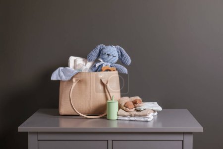 Mother's bag with baby's stuff on commode near gray wall