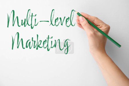 Photo for Woman writing text Multi Level Marketing on white background, closeup - Royalty Free Image