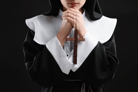Foto de Monja con cruz rezando a Dios sobre fondo negro, primer plano - Imagen libre de derechos