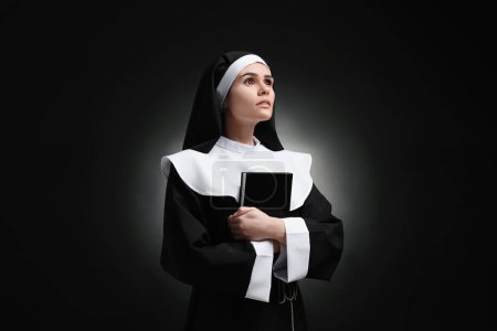 Foto de Joven monja con Biblia sobre fondo negro - Imagen libre de derechos
