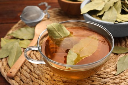 Téléchargez les photos : Tasse de thé fraîchement infusé avec des feuilles de laurier sur tapis d'osier, gros plan - en image libre de droit