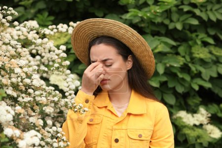 Frau leidet an saisonaler Pollenallergie in der Nähe blühender Bäume am Frühlingstag