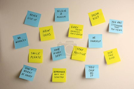 Paper notes with life-affirming phrases on white wall