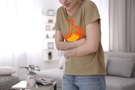 Foto de Mujer que sufre de acidez estomacal en casa, primer plano. Estómago con lava que simboliza indigestión ácida, ilustración - Imagen libre de derechos