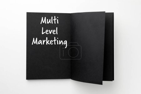 Téléchargez les photos : Multi Level Marketing écrit dans un carnet avec des pages noires sur fond blanc, vue du dessus - en image libre de droit