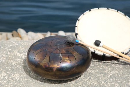 Different drums, soft mallet and drumstick near sea. Percussion musical instruments