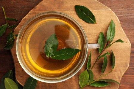 Téléchargez les photos : Tasse de thé fraîchement infusé avec des feuilles de laurier sur une table en bois, plat - en image libre de droit