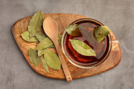 Téléchargez les photos : Tasse de thé fraîchement infusé avec des feuilles de laurier sur table grise, vue de dessus - en image libre de droit