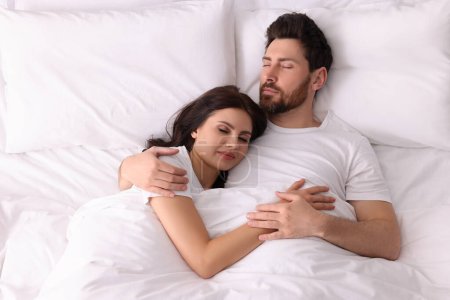 Lovely couple sleeping together in bed at home, top view