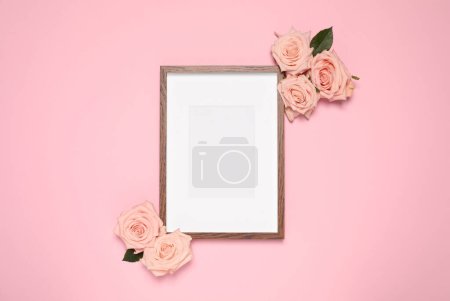 Téléchargez les photos : Cadre photo vide et belles roses sur fond rose, pose plate. Maquette pour le design - en image libre de droit