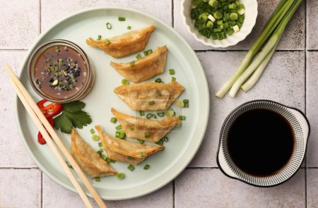 Téléchargez les photos : Délicieux gyoza (boulettes asiatiques) servi sur table carrelée légère, plat - en image libre de droit
