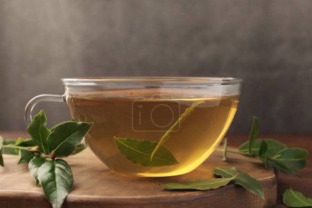 Téléchargez les photos : Tasse de thé fraîchement infusé avec des feuilles de laurier sur planche de bois, gros plan - en image libre de droit