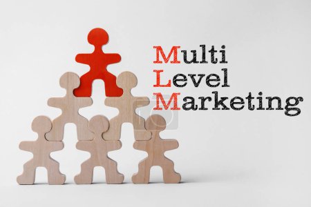 Téléchargez les photos : Marketing multi-niveaux. Pyramide de figures humaines en bois avec une rouge en haut montrant la hiérarchie sur la table blanche - en image libre de droit