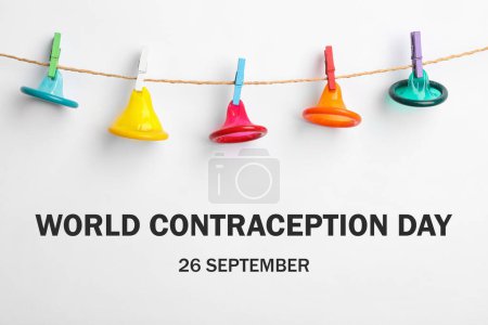 Foto de Día Mundial de la Anticoncepción. Preservativos coloridos colgando en el tendedero sobre fondo blanco - Imagen libre de derechos