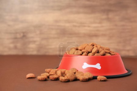 Nourriture sèche pour chien et bol d'alimentation sur une table brune. Espace pour le texte