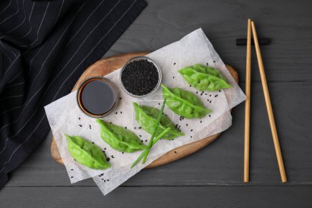 Téléchargez les photos : Délicieuses boulettes vertes (gyozas) servies sur une table en bois gris, à plat - en image libre de droit