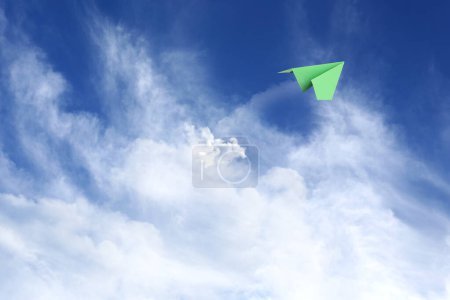 White clouds and paper airplane flying in blue sky on sunny day. Space for text