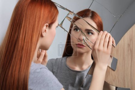 Photo for Sad young woman suffering from mental problems near broken mirror - Royalty Free Image