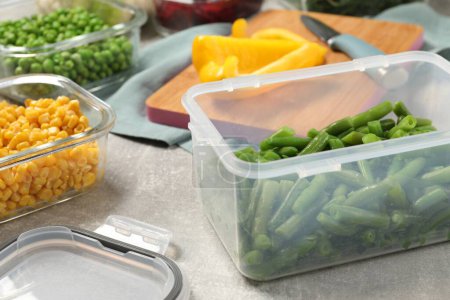 Photo for Containers with green beans and fresh products on light gray table, closeup. Food storage - Royalty Free Image