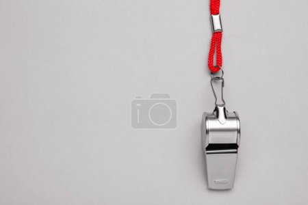 Foto de Un silbato de metal con cordón rojo sobre fondo gris claro, vista superior. Espacio para texto - Imagen libre de derechos