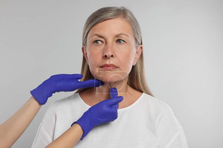 Foto de Endocrinólogo examinando la glándula tiroides del paciente sobre fondo gris claro, primer plano - Imagen libre de derechos