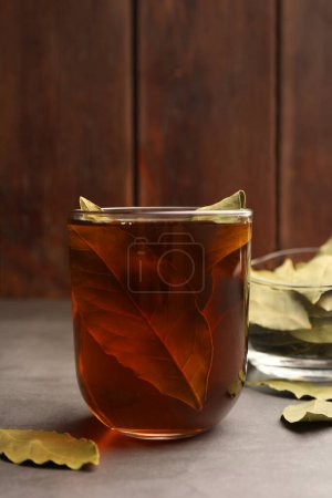 Téléchargez les photos : Tasse de thé fraîchement infusé avec feuilles de laurier sur table grise - en image libre de droit