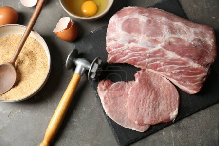 Téléchargez les photos : Côtelettes de porc crues et ingrédients pour faire cuire le schnitzel sur une table grise, plat - en image libre de droit