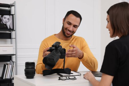 Téléchargez les photos : Jeune photographe professionnel montrant l'appareil photo à la femme dans un studio photo moderne - en image libre de droit