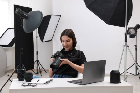 Téléchargez les photos : Jeune photographe professionnel avec appareil photo à table dans un studio photo moderne - en image libre de droit