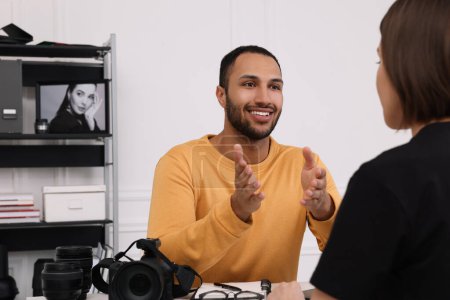 Téléchargez les photos : Jeune photographe professionnel avec appareil photo parler avec une femme dans un studio photo moderne - en image libre de droit