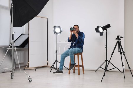 Téléchargez les photos : Jeune photographe professionnel prenant des photos dans un studio photo moderne - en image libre de droit