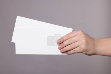 Woman holding flyers on grey background, closeup. Mockup for design