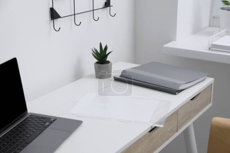 Photo for Punched pockets, folders and laptop on white table in office - Royalty Free Image