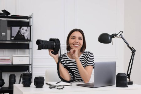 Téléchargez les photos : Jeune photographe professionnel avec appareil photo travaillant sur ordinateur portable dans un studio photo moderne - en image libre de droit