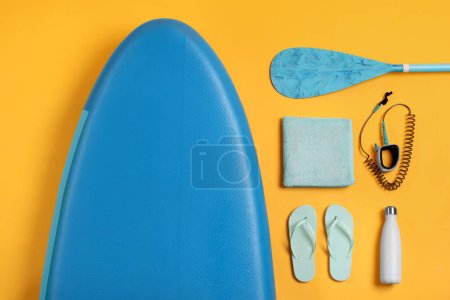 Flat lay composition with SUP board on yellow background. Water sport