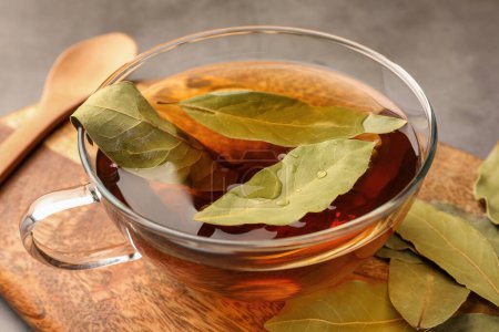 Téléchargez les photos : Tasse de thé fraîchement infusé avec des feuilles de laurier sur planche de bois, gros plan - en image libre de droit
