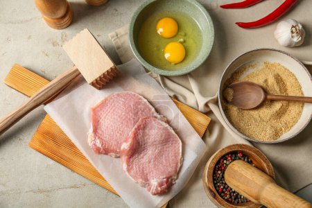 Téléchargez les photos : Côtelettes de porc crues, maillet de viande et ingrédients pour la cuisson de schnitzel sur table grise, plat - en image libre de droit