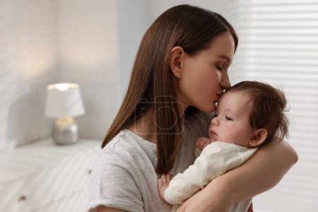 Glückliche Mutter küsst ihr kleines Baby zu Hause
