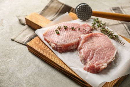 Téléchargez les photos : Schnitzel de cuisine. Côtelettes de porc crues, thym et maillet de viande sur table grise - en image libre de droit