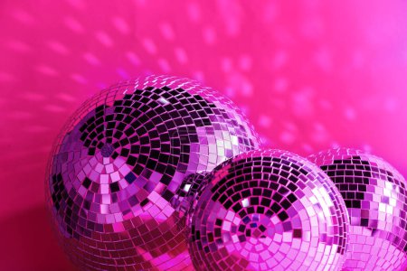 Many shiny disco balls near color wall, toned in pink
